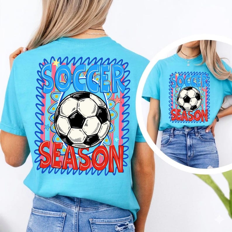 Puede incluir: Camiseta azul claro con un dise&ntilde;o de bal&oacute;n de f&uacute;tbol. El dise&ntilde;o incluye las palabras "SOCCER SEASON" en un dise&ntilde;o colorido. La camiseta es de manga corta y est&aacute; hecha de un material suave.