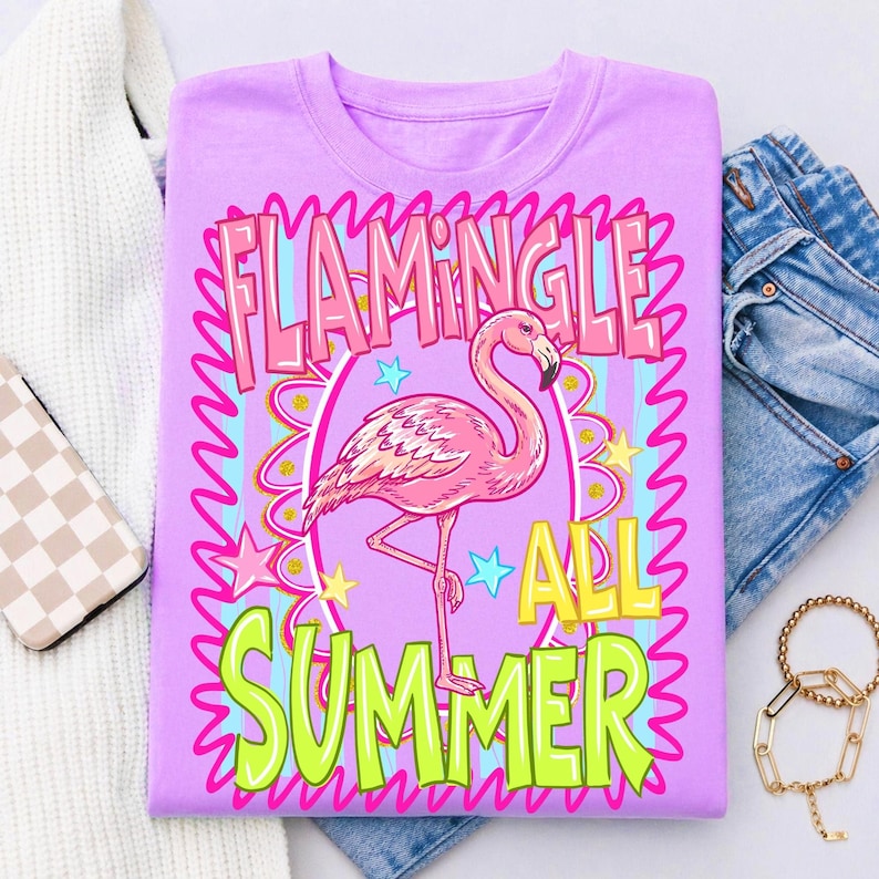 Puede incluir: Camiseta lila con un dise&ntilde;o de flamenco rosa y la frase "Flamingle All Summer". El dise&ntilde;o incluye estrellas y un borde ondulado. Tema veraniego.