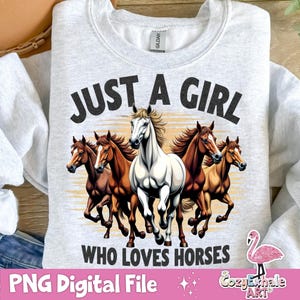 May include: A gray sweatshirt with the text "Just a girl who loves horses" printed on the front. The text is in black and there are five horses in the background. The horses are brown, white, and black.