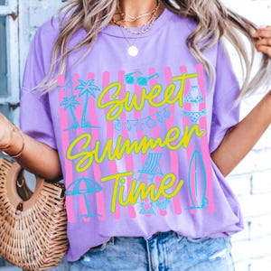 Może przedstawiać: Liliowa koszulka z napisem "Sweet Summer Time" w ż&oacute;łtym kolorze, ozdobiona turkusowymi i r&oacute;żowymi grafikami okular&oacute;w przeciwsłonecznych, palm i akcesori&oacute;w plażowych. Projekt umieszczono na r&oacute;żowych, pionowych paskach.