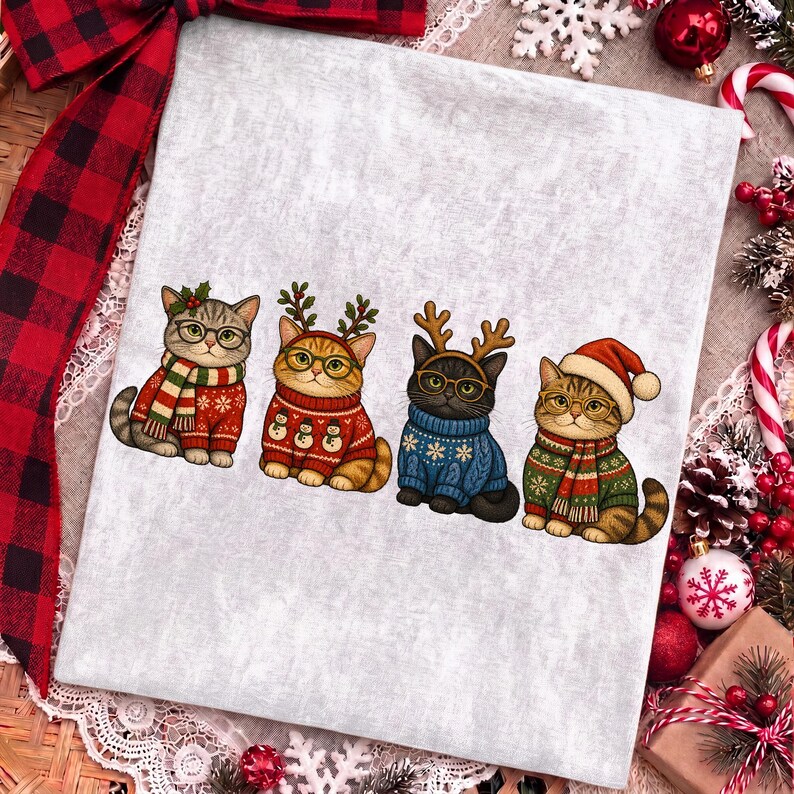 K&ouml;nnte beinhalten: Ein hellgraues T-Shirt mit einer Grafik von vier Katzen, die Brillen und Weihnachtspullover tragen. Die erste Katze tr&auml;gt einen rot-gr&uuml;nen Schal, die zweite ein Rentiergeweih, die dritte ein Geweih und einen blauen Pullover, die vierte eine Weihnachtsm&uuml;tze.