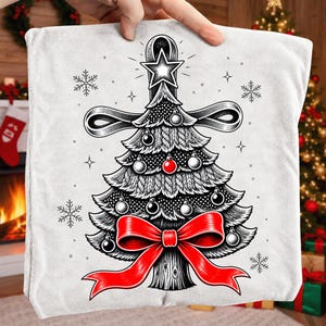 K&ouml;nnte beinhalten: Ein wei&szlig;er Stoffartikel mit einer schwarz-wei&szlig;en grafischen Illustration eines stilisierten Weihnachtsbaums mit Zopfmuster-Textur, verziert mit einer gro&szlig;en roten Schleife an der Basis, einer roten Kugel, silbernen Kugeln und einem Stern.
