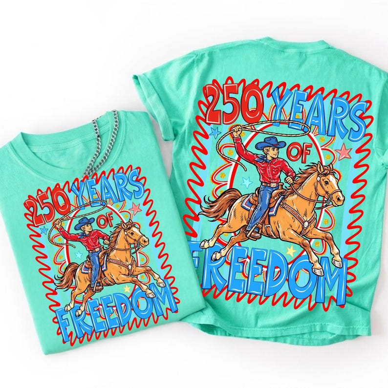 Puede incluir: Dos camisetas turquesas con un dise&ntilde;o gr&aacute;fico. El dise&ntilde;o presenta a un vaquero montando a caballo con un lazo, rodeado por el texto "250 YEARS OF FREEDOM" en rojo y azul. Una camiseta est&aacute; doblada, la otra est&aacute; plana.