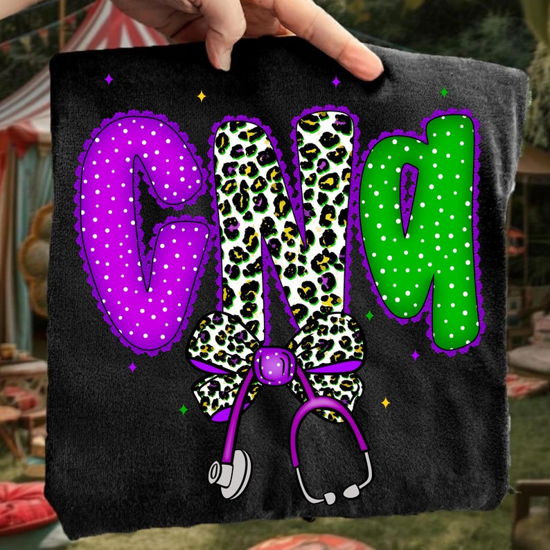 May include: Black pillow with the letters "GND" in purple, leopard print, and green. The letters are decorated with polka dots and a purple bow with a stethoscope. The design includes small star accents.