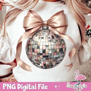 May include: A white sweatshirt with a pink and gold glitter disco ball ornament with a large pink and gold bow. The ornament is centered on the sweatshirt.