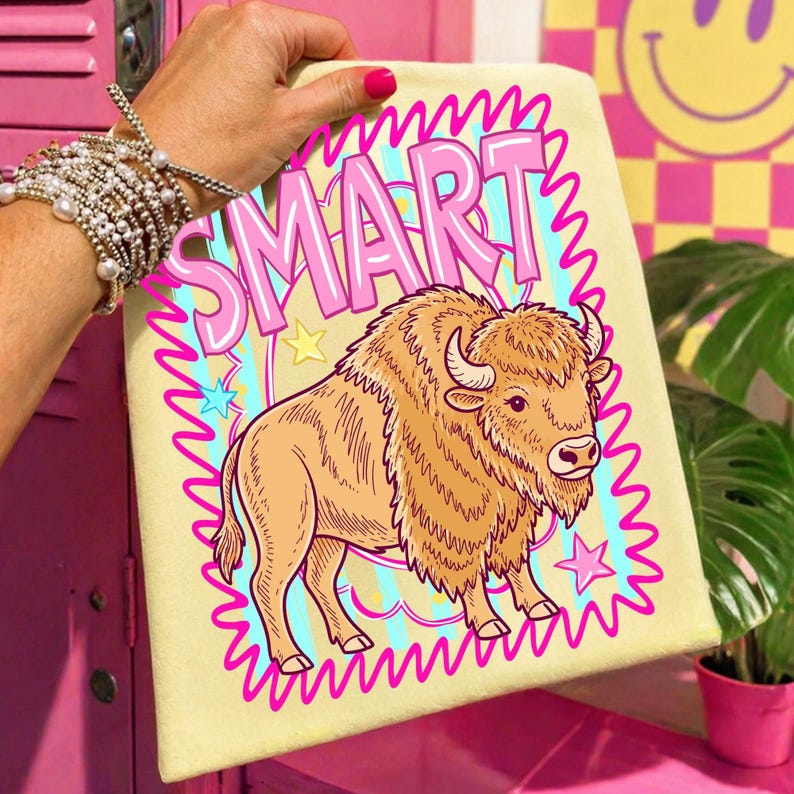 May include: A light yellow canvas with the word "SMART" in pink bubble letters, and a cartoon bison illustration. The bison is tan with a fluffy mane and horns. The design is framed with a wavy pink border and stars.