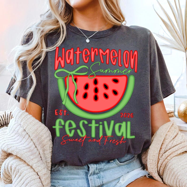 以下が含まれることがあります： スイカのデザインが施された濃いグレーのTシャツ。「Watermelon Summer Festival」の文字が赤と緑で描かれ、スイカのスライスのイラストと「Sweet and Fresh」の文字がデザインされています。