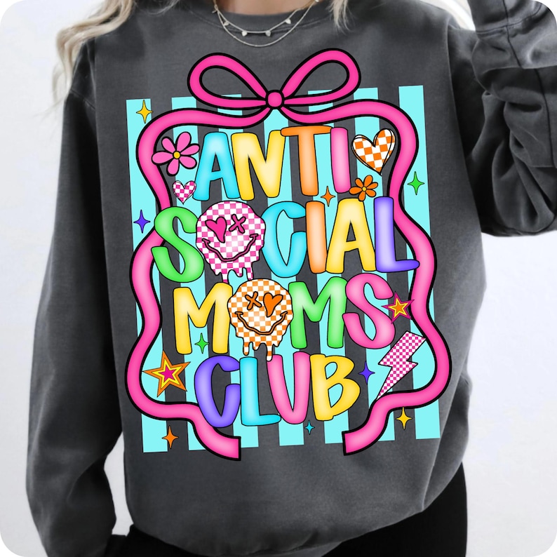 K&ouml;nnte beinhalten: Dunkelgraues Sweatshirt mit einem farbenfrohen Aufdruck "ANTI SOCIAL MOMS CLUB". Das Design umfasst ein rosa Band, Blumen, Herzen, Sterne und Smiley-Gesichter. Der Text ist in verschiedenen leuchtenden Farben gehalten.