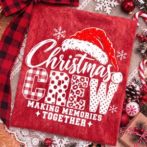 May include: A red shirt featuring a white graphic of a Santa hat and the text Christmas CREW MAKING MEMORIES TOGETHER. The letters in CREW feature varied patterns including buffalo plaid, polka dots, and leopard print with white snowflakes.