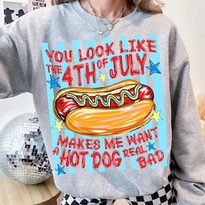 May include: A gray sweatshirt with a graphic of a hot dog and the text "YOU LOOK LIKE THE 4TH OF JULY MAKES ME WANT A HOT DOG REAL BAD". The hot dog is in a bun with mustard.