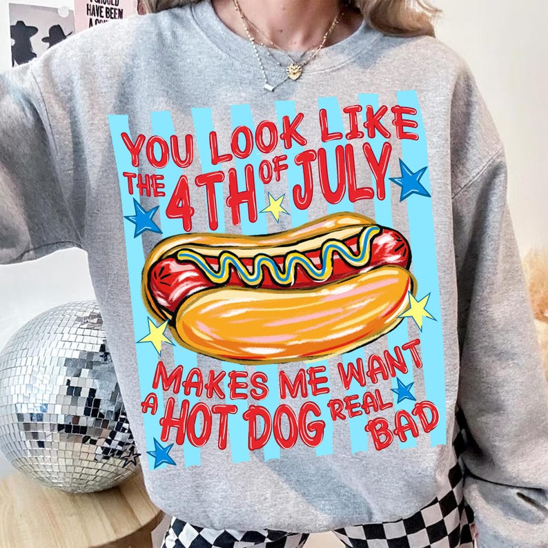 May include: A gray sweatshirt with a graphic of a hot dog and the text "YOU LOOK LIKE THE 4TH OF JULY MAKES ME WANT A HOT DOG REAL BAD". The hot dog is in a bun with mustard.