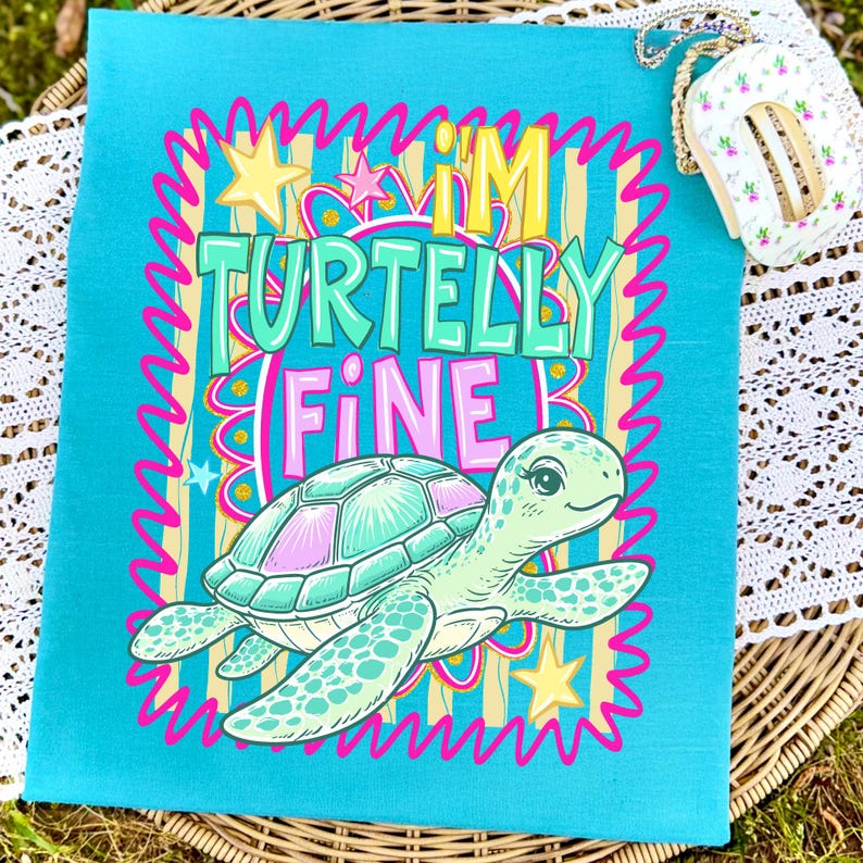 May include: A turquoise tote bag with a cartoon turtle illustration and the phrase "I'M TURTELLY FINE" in colorful text. The turtle is light green and pink, with a smiling face. The background has vertical stripes and stars.