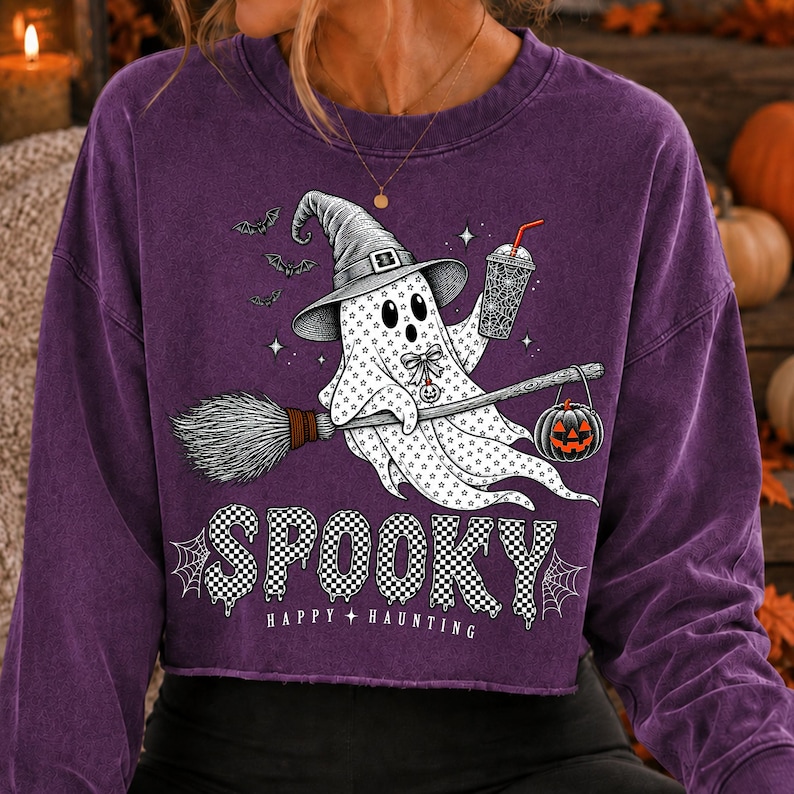 May include: A purple long-sleeve sweatshirt featuring a graphic of a ghost wearing a witch hat, holding a drink and a broomstick with a jack-o'-lantern. The text reads SPOOKY HAPPY HAUNTING, accompanied by small bats, stars, and spider web designs.