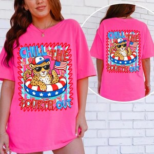 Op de afbeelding: Een felroze t-shirt met een afbeelding van een luipaard met een zonnebril en een patriotische hoed, drijvend in een rood, wit en blauw zwemband, met een Amerikaanse vlag. De tekst luidt "Chill the Fourth Out".