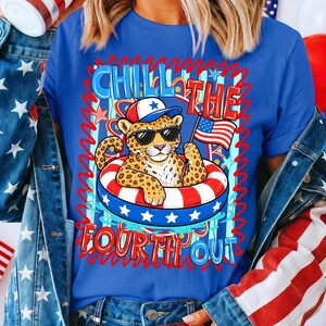 Op de afbeelding: Blauw T-shirt met een luipaard met zonnebril en hoed, drijvend in een rood, wit en blauw zwemband. De tekst "CHILL THE FOURTH OUT" staat boven en onder de luipaard. Het shirt heeft een patriottisch thema.