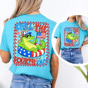K&ouml;nnte beinhalten: Ein hellblaues T-Shirt mit einem Cartoon-Alligator, der eine Sonnenbrille und einen patriotischen Hut tr&auml;gt und auf einem rot-wei&szlig;-blauen Schwimmreifen schwimmt. Das Shirt tr&auml;gt den Text "Chill the Fourth Out" in Rot und Blau.