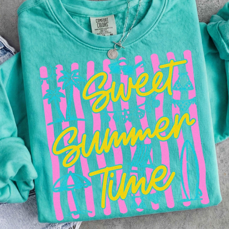 Może przedstawiać: Turkusowa bluza Comfort Colors z napisem "Sweet Summer Time" w ż&oacute;łtym skrypcie. R&oacute;żowe pionowe paski i letnie ilustracje, w tym palmy i deski surfingowe, znajdują się z przodu. Widoczny jest r&oacute;wnież srebrny naszyjnik z wisiorkiem.