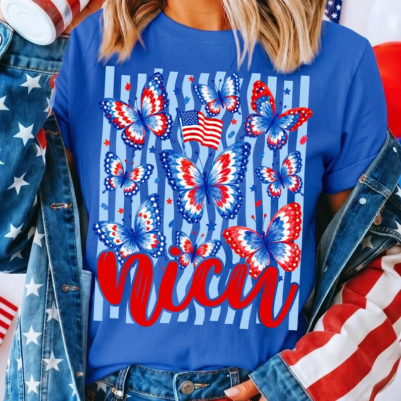 Peut inclure: Un t-shirt bleu roi avec une impression graphique de plusieurs papillons aux motifs rouges, blancs et bleus. Le design comprend un petit drapeau am&eacute;ricain et des rayures verticales bleu clair. Le mot "nicu" est &eacute;crit en grande &eacute;criture cursive rouge.