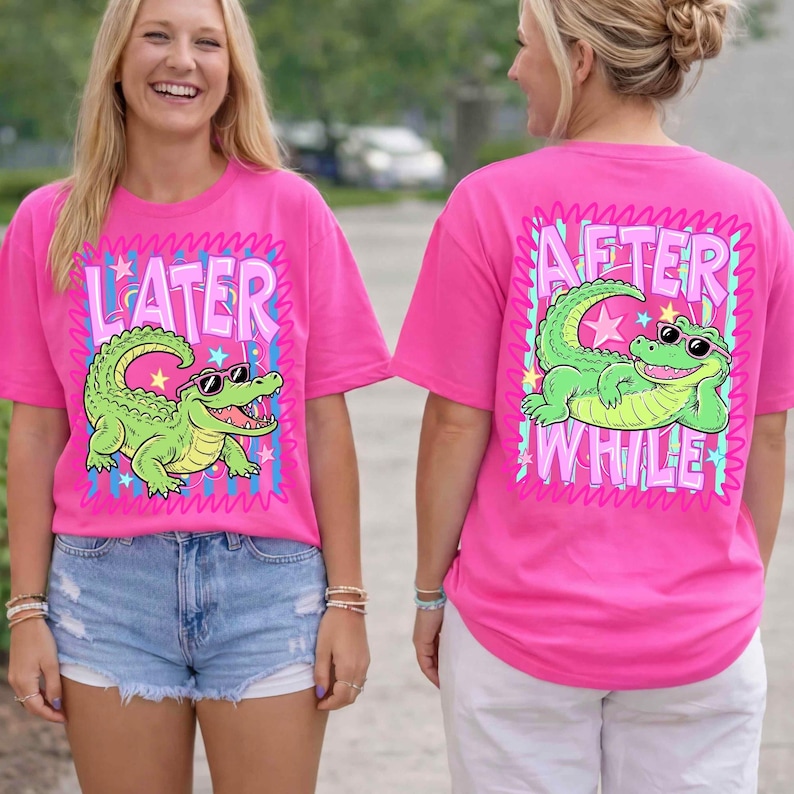 May include: Bright pink t-shirts with a cartoon alligator wearing sunglasses. One shirt says "LATER" and the other says "AFTER WHILE". The alligator is green with a white belly and is surrounded by a pink and blue design.
