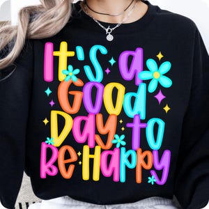 K&ouml;nnte beinhalten: Schwarzer Pullover mit einer bunten Grafik, auf der "It's a good day to be happy" steht.