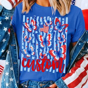 Peut inclure: Un t-shirt bleu roi avec une impression graphique de plusieurs papillons aux motifs d'ailes rouges, blancs et bleus. Le design inclut un petit drapeau am&eacute;ricain et des rayures verticales bleu clair. Le mot custom est &eacute;crit en lettres cursives rouges.