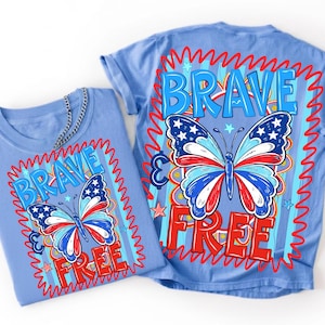 May include: Two light blue t-shirts with a patriotic butterfly design. The butterfly wings feature red, white, and blue colours with stars. The word "BRAVE" is above the butterfly, and "FREE" is below it, in red letters.