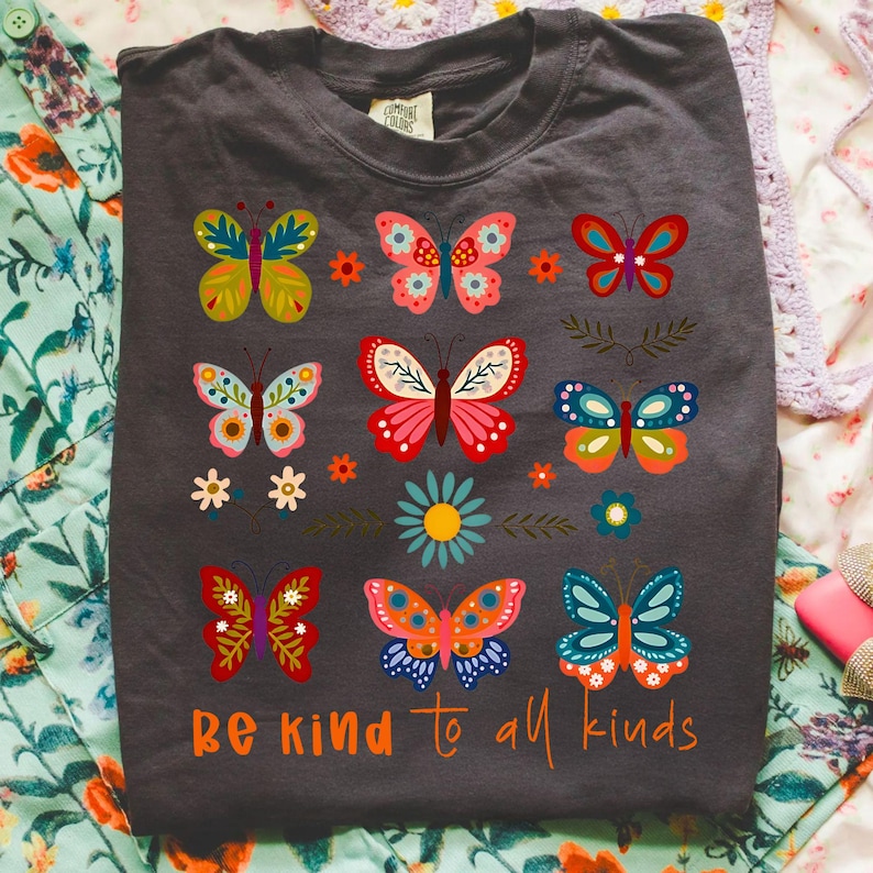 Mockup of the 'Be Kind to All Kinds' boho butterfly and wildflower design applied to a t-shirt.