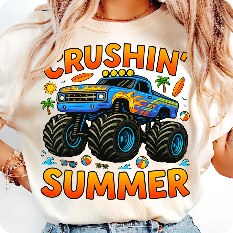 May include: Cream-colored t-shirt featuring a blue monster truck with flames and the words "Crushin' Summer" in orange and yellow. The design includes palm trees, surfboards, and beach balls.