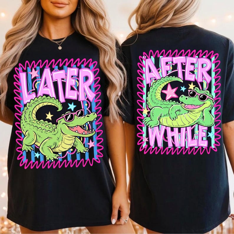 May include: Black t-shirt featuring a cartoon alligator wearing sunglasses. The front of the shirt has the word "LATER" and the alligator graphic. The back of the shirt has the words "AFTER WHILE" and the alligator graphic. The design is outlined in pink.