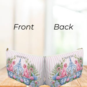 May include: A zippered pouch featuring a light pink and white striped background with a repeating pattern of pink monkeys, blue and white porcelain vases, green bamboo, and pink and blue hydrangea flowers, with the word MAHJONG printed on it.