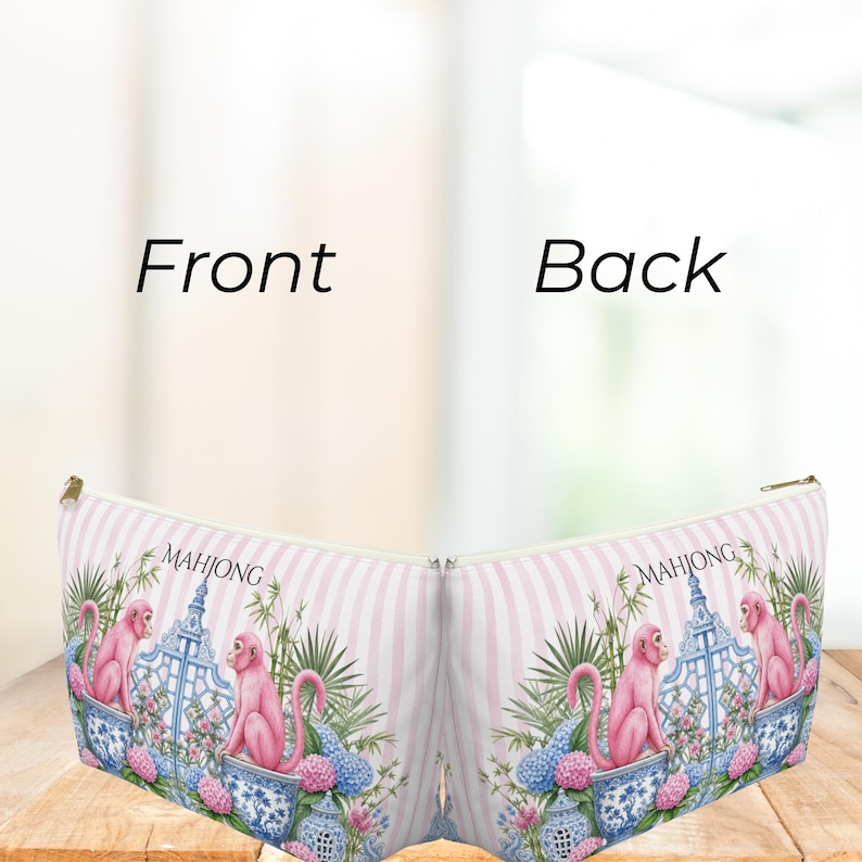 May include: A zippered pouch featuring a light pink and white striped background with a repeating pattern of pink monkeys, blue and white porcelain vases, green bamboo, and pink and blue hydrangea flowers, with the word MAHJONG printed on it.