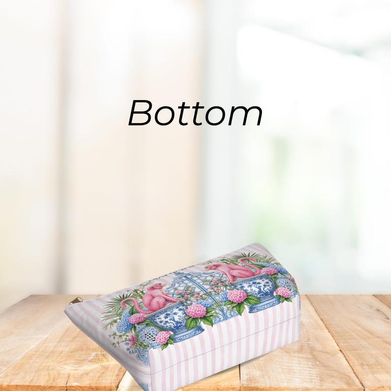 May include: A rectangular zippered pouch featuring a light pink and white striped pattern. The design displays pink monkeys perched on blue and white decorative ceramic garden stools, surrounded by green foliage and clusters of pink and blue flowers.