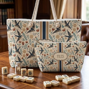 May include: A tote bag and a matching zippered pouch featuring a cream background with a pattern of blue swallows, red flowers, and tan circular motifs. Both items have a central vertical navy blue stripe and white rope handles.