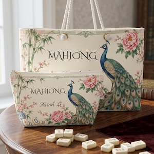 May include: A cream-colored tote bag and a matching zippered pouch, both featuring a printed design of a peacock, pink peonies, and bamboo stalks. The text "MAHJONG" is printed on both items, and the pouch includes the name "Sarah" in script.