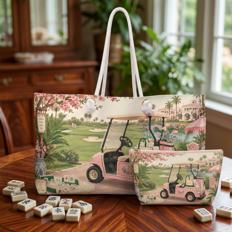 May include: A large tote bag and a smaller matching pouch featuring a printed scene of a pink golf cart on a golf course with palm trees, blooming cherry blossom trees, and mahjong tiles scattered on the ground in the foreground.
