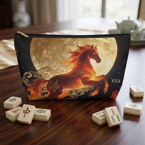May include: A black zipped pouch featuring a graphic of a fiery horse galloping in front of a large, glowing full moon. The design includes swirling cloud patterns and the name Rita printed in white. The pouch is surrounded by mahjong tiles.