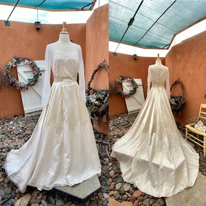 May include: A vintage ivory satin wedding dress with long sleeves and a lace overlay. The dress has a fitted bodice and a full skirt. The back of the dress features a button closure.