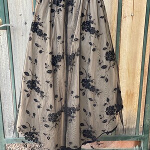 May include: A black tulle skirt with a floral pattern. The skirt is gathered at the waist and has a full, flowing silhouette.