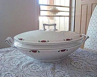 May include: White oval serving dish with a lid. The dish has a red and green floral design around the rim. The lid has two handles.