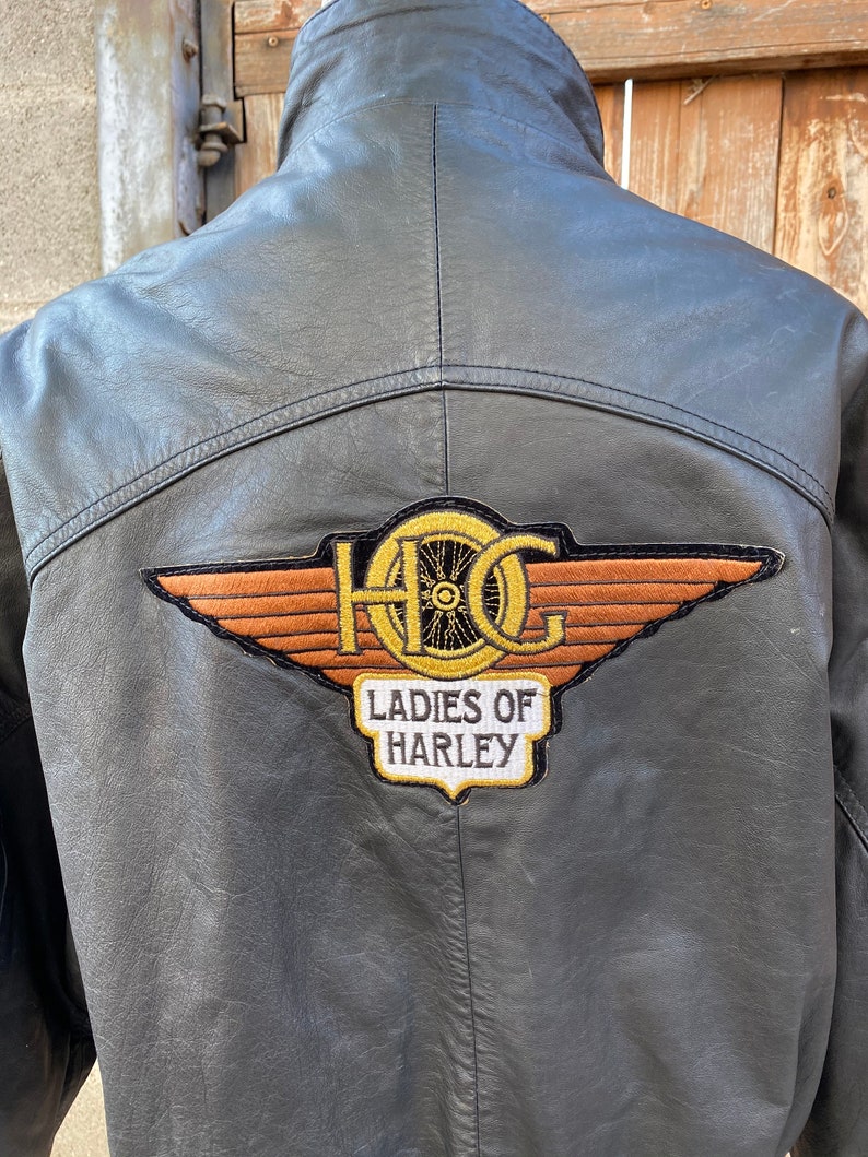 Puede incluir: Chaqueta de cuero negra con un gran parche bordado en la espalda que dice "HOG Ladies of Harley".