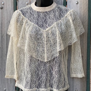 May include: A white lace top with a ruffled neckline and long sleeves.