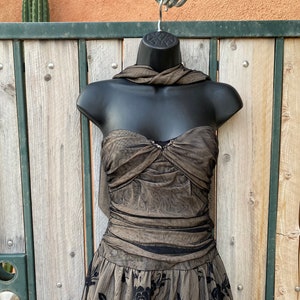 May include: A brown and black strapless dress with a floral pattern. The dress has a fitted bodice and a flowing skirt.