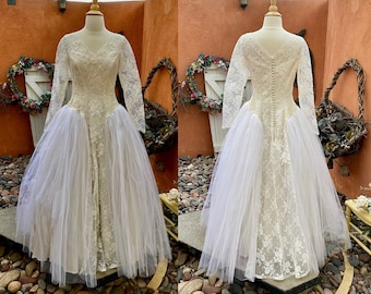 Könnte beinhalten: Ein Vintage-Hochzeitskleid aus weißer Spitze mit langen Ärmeln und einem Tüllrock. Das Kleid hat einen V-Ausschnitt und ein tailliertes Oberteil. Der Rock ist voll und fließend.