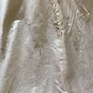 May include: A white satin skirt with a lace trim and small, clear embellishments.
