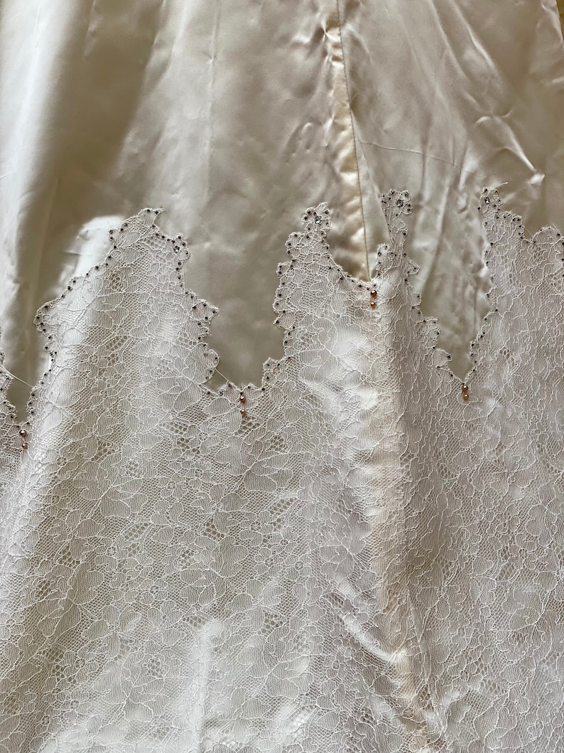 May include: A white satin skirt with a lace trim and small, clear embellishments.