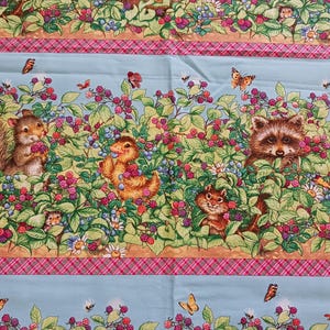 May include: A blue and green fabric with a repeating pattern of animals and berries. The animals include a squirrel, a duck, a raccoon, and a chipmunk. The berries are red and blue. The fabric has a pink and white plaid border.
