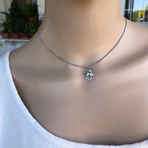 May include: A silver chain necklace with a small angel pendant.
