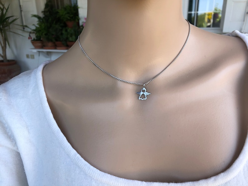 May include: A silver chain necklace with a small angel pendant.