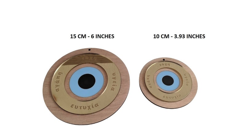 May include: Two round wooden ornaments with a blue evil eye design. The larger ornament is 6 inches in diameter and the smaller ornament is 3.93 inches in diameter. Both ornaments have gold lettering around the evil eye that reads "agapi", "tyhi", "ygeia", and "eytyhia".