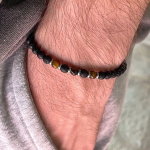 Peut inclure: Un bracelet en perles de lave noire et d'œil de tigre avec des accents argentés.